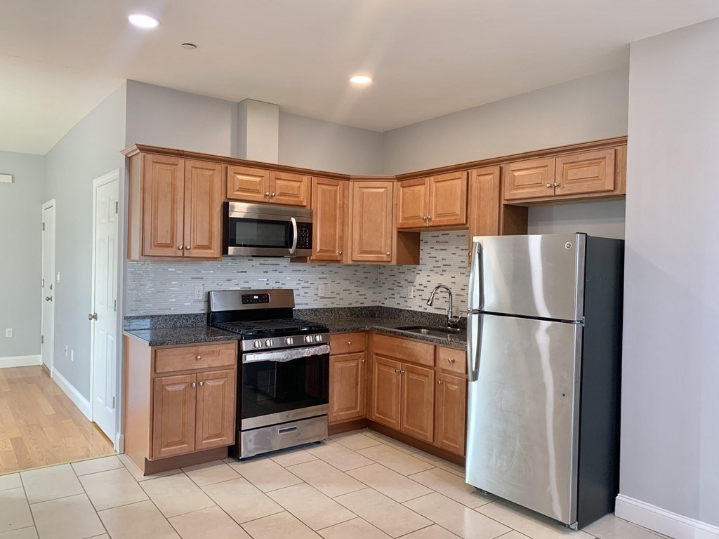 a kitchen with granite countertop a refrigerator stove and microwave