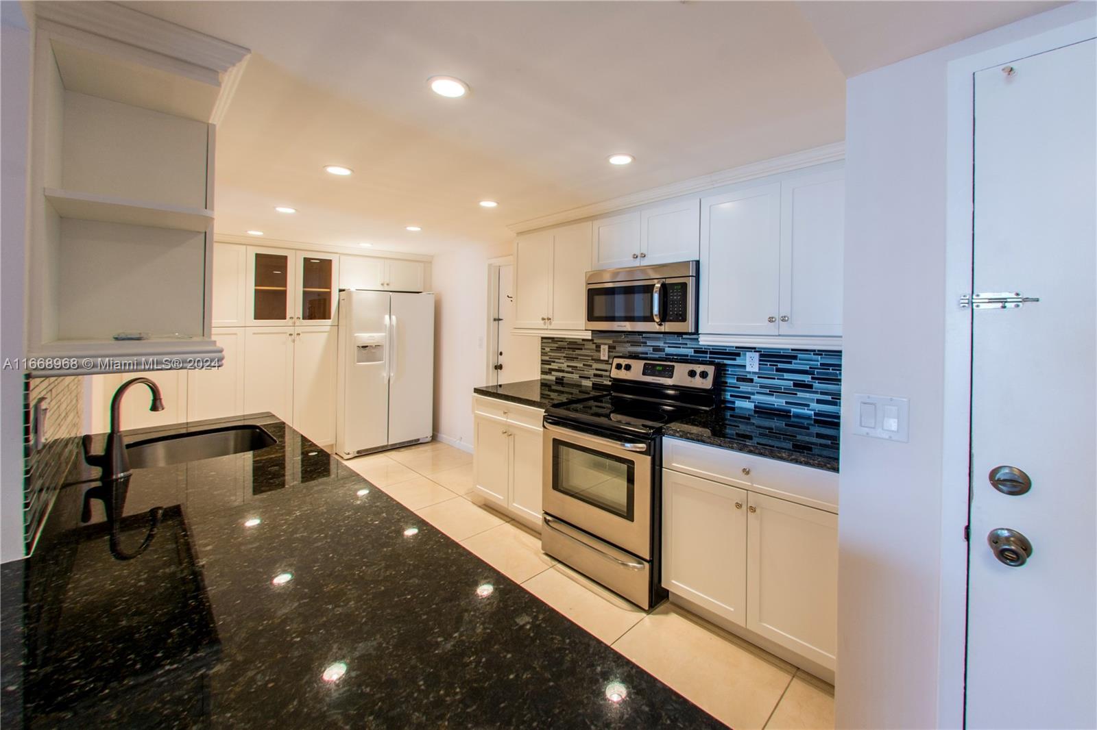 a kitchen with stainless steel appliances granite countertop a sink a stove and a refrigerator