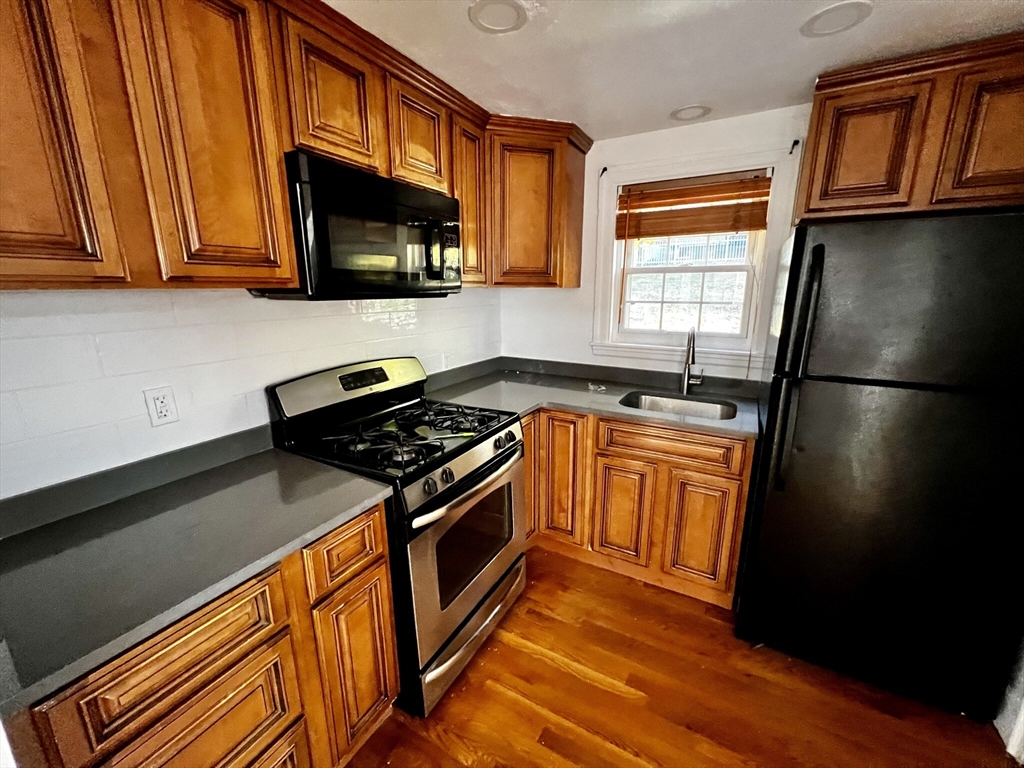 a kitchen with stainless steel appliances granite countertop a stove a sink and a microwave