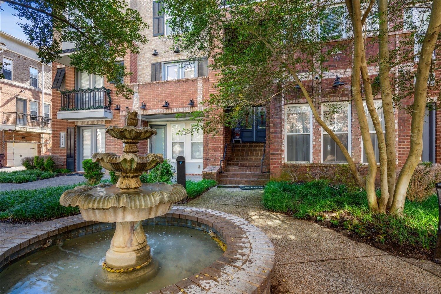 a front view of a house with garden fountain and trees