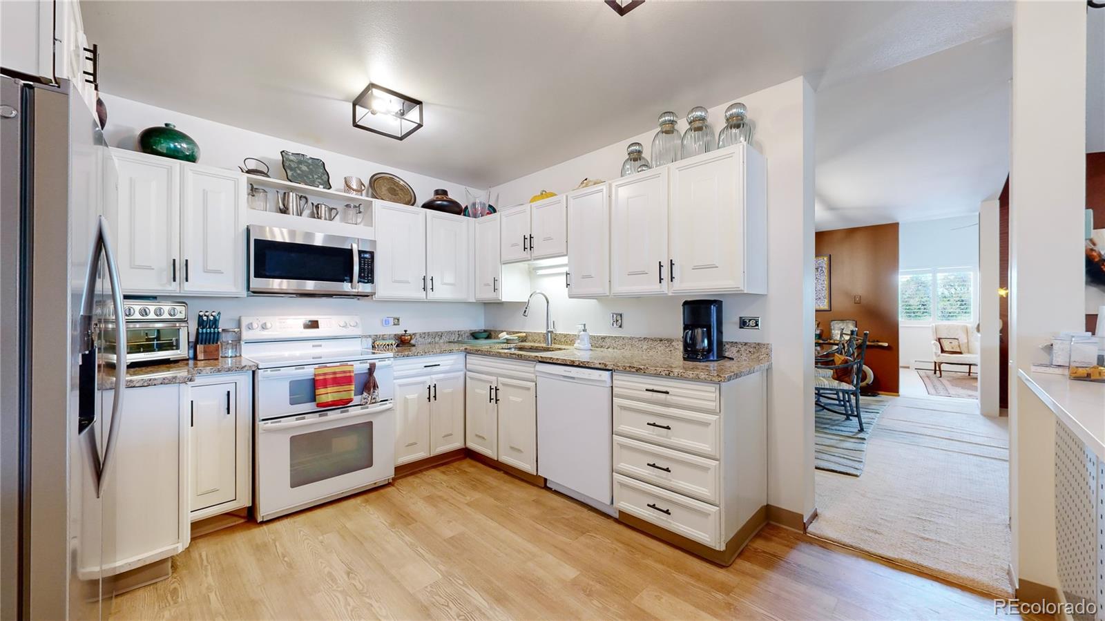 a kitchen with stainless steel appliances a white cabinets and wooden floor