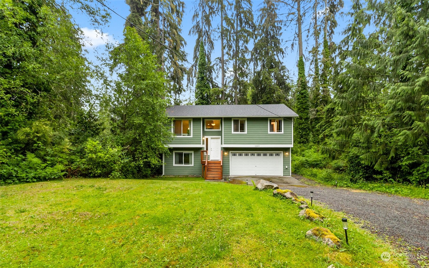 a view of a house with a small yard plants and large tree