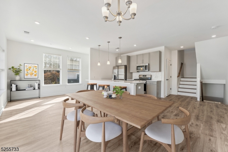 a kitchen with stainless steel appliances granite countertop a dining table chairs and stove top oven