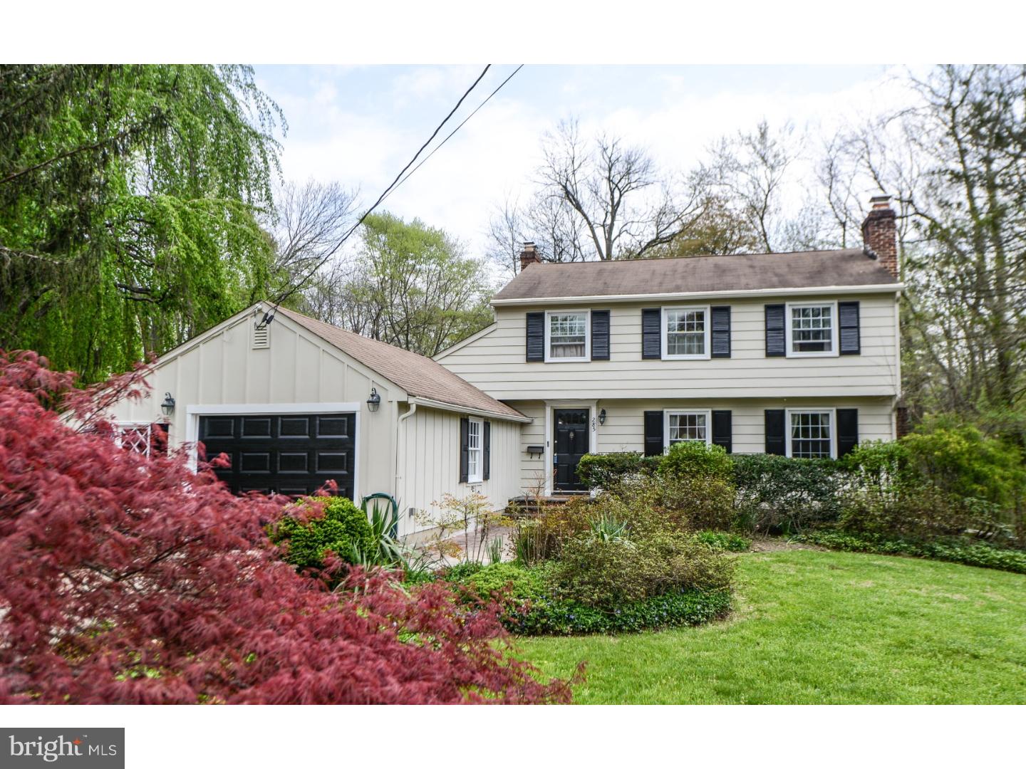 a view of a white house next to a yard with potted plants