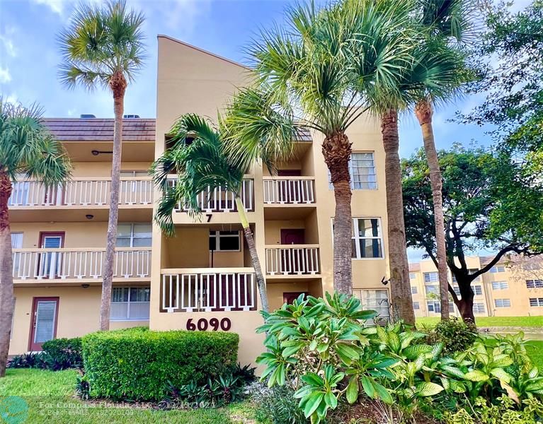 front view of a house with a yard and palm trees