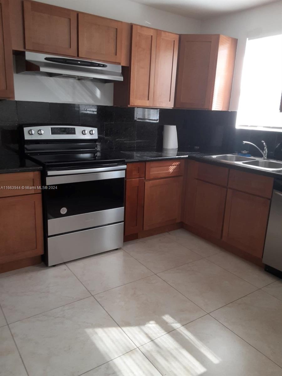 a kitchen with granite countertop a stove and a sink