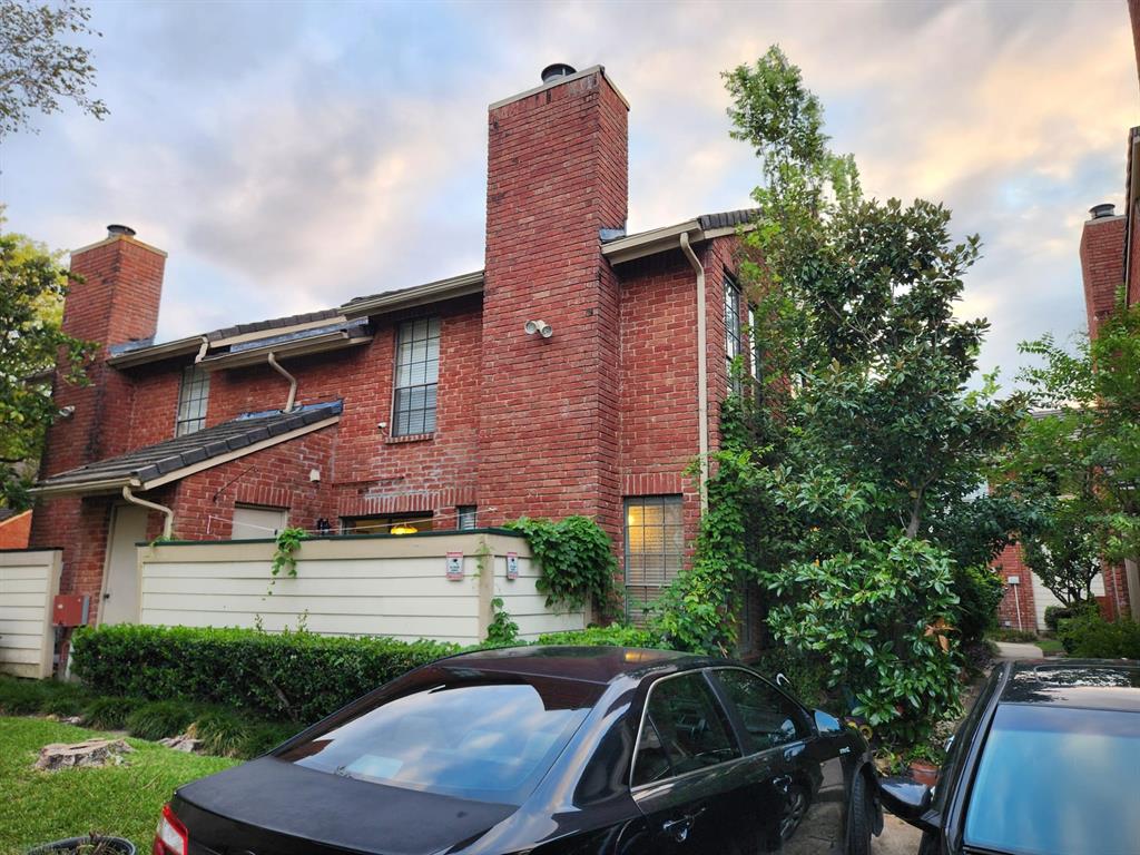 a view of a brick house with a yard plants and a table and chairs