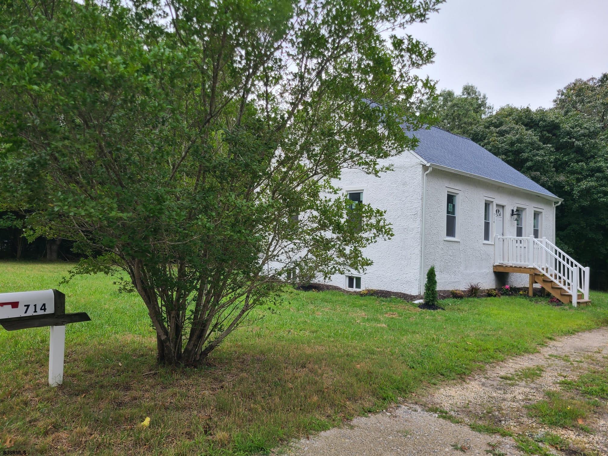 a white house with a small yard and large trees