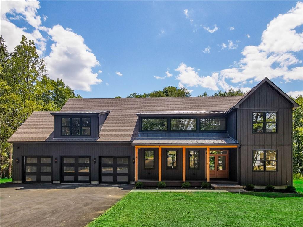 Modern farmhouse style home featuring a front lawn and a garage