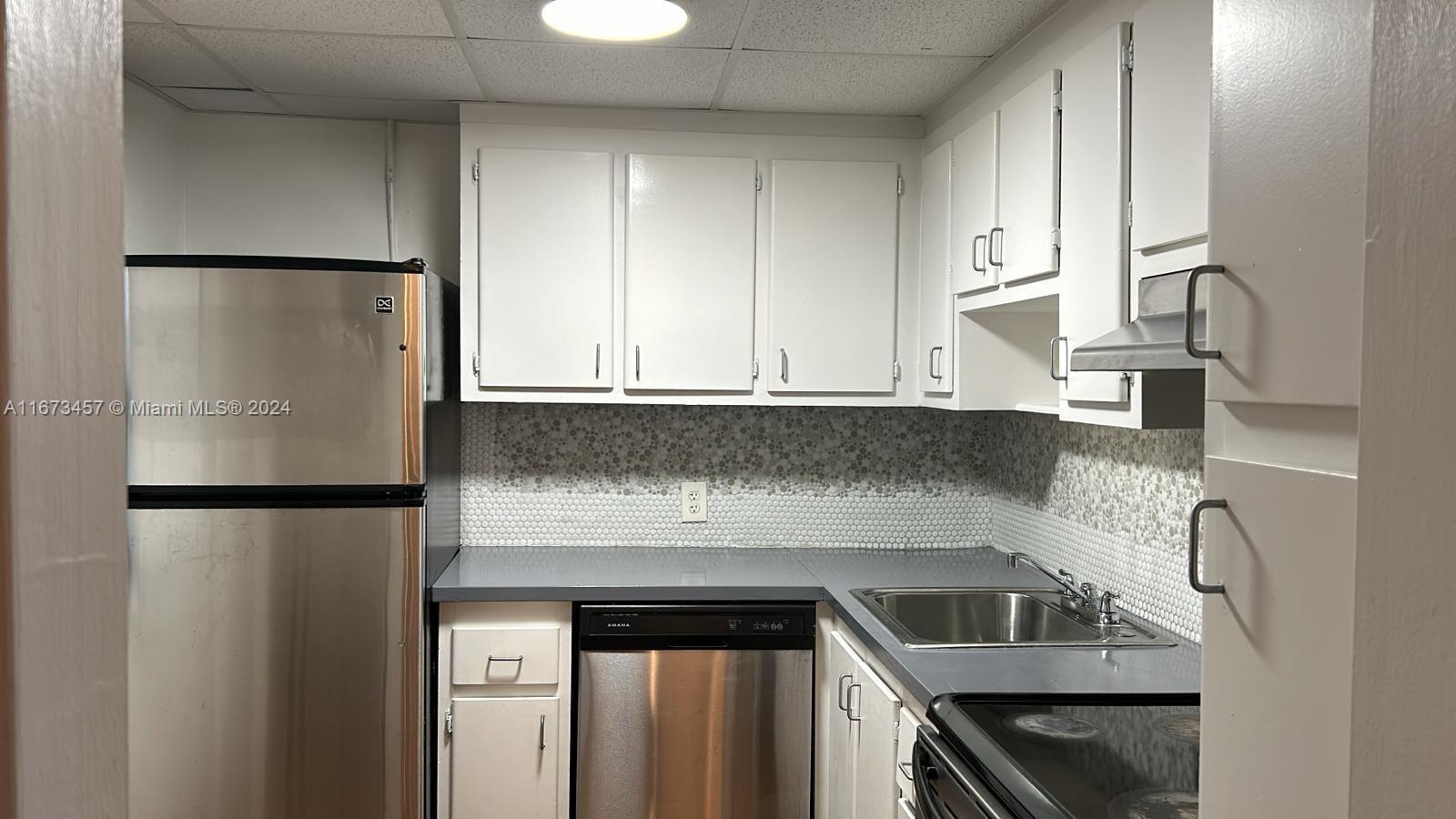 a kitchen with a refrigerator sink and cabinets