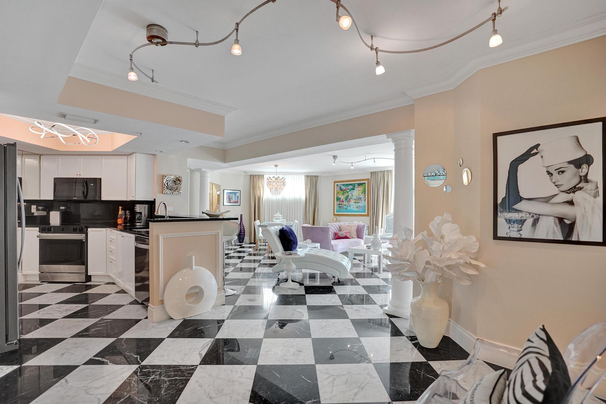 a living room with a black white checkered floor with couches chair and a coffee table