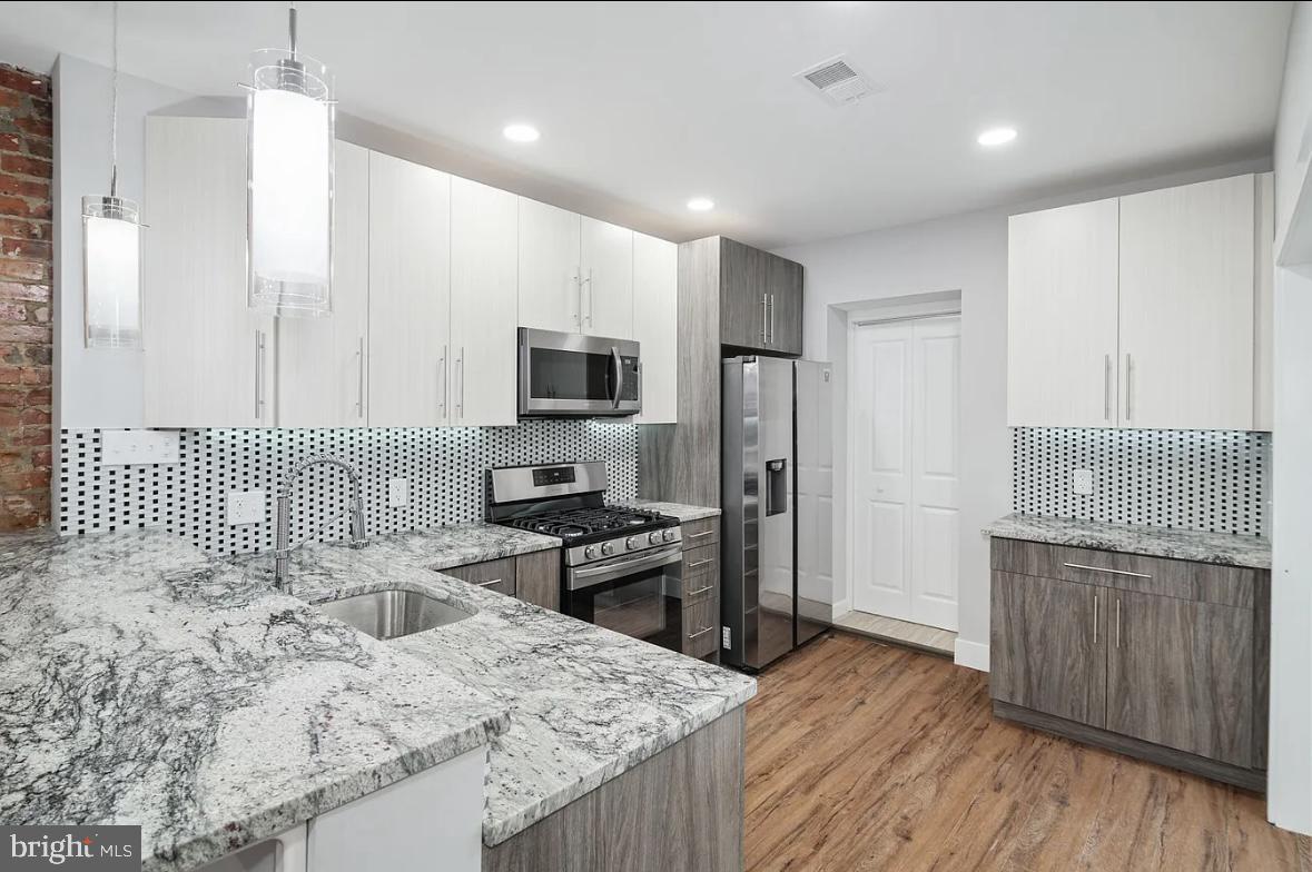 a kitchen with stainless steel appliances kitchen island granite countertop a sink stove and refrigerator