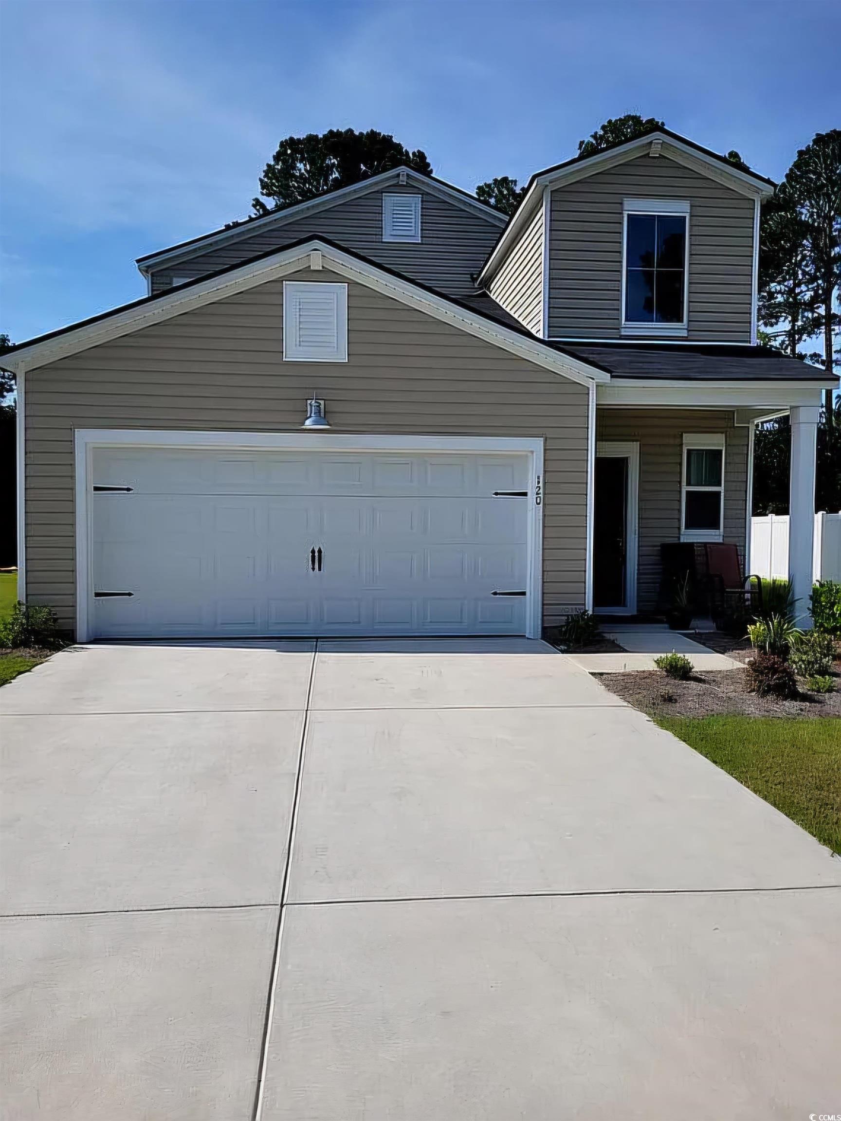 View of front of home with covered porch and a gar