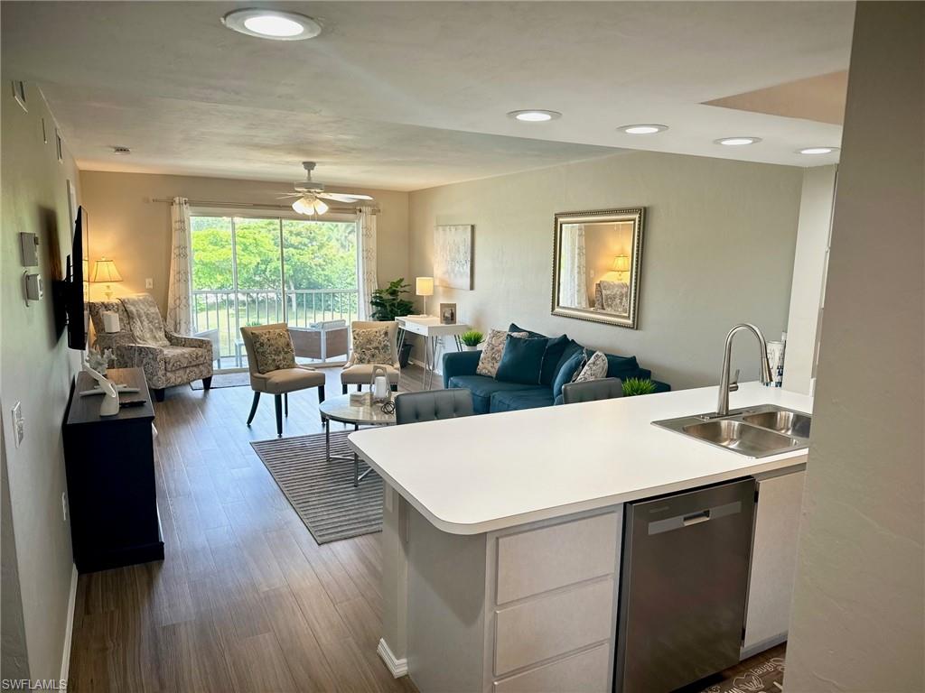 a living room with furniture a large window and wooden floor