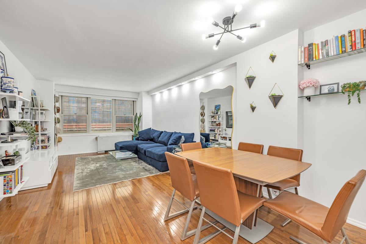 a living room with couches and kitchen view with wooden floor