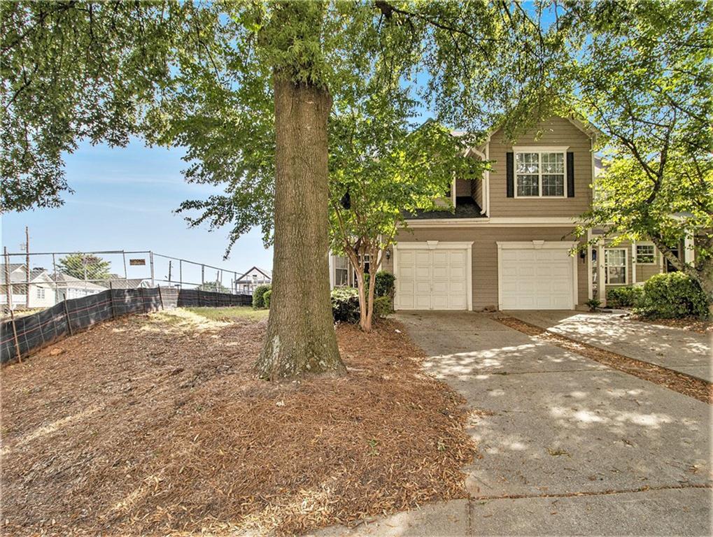 a view of a house with a yard and large tree