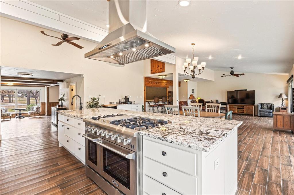 a large kitchen with stainless steel appliances granite countertop a lot of counter space and wooden floors