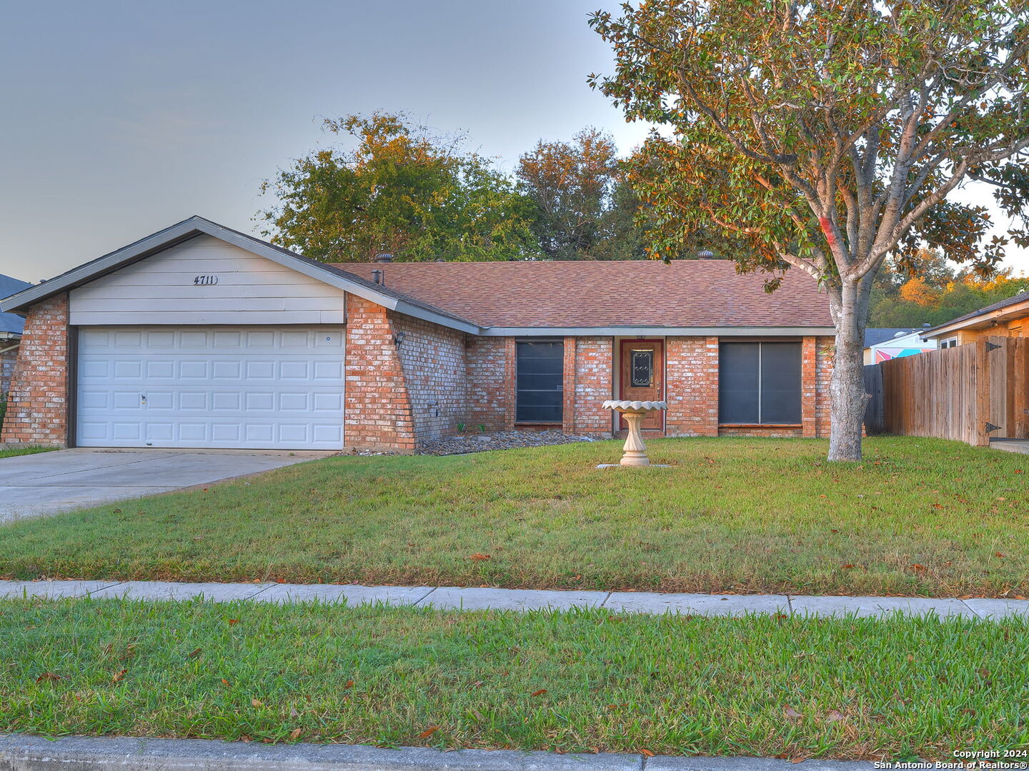 a brick house next to a yard with a large tree