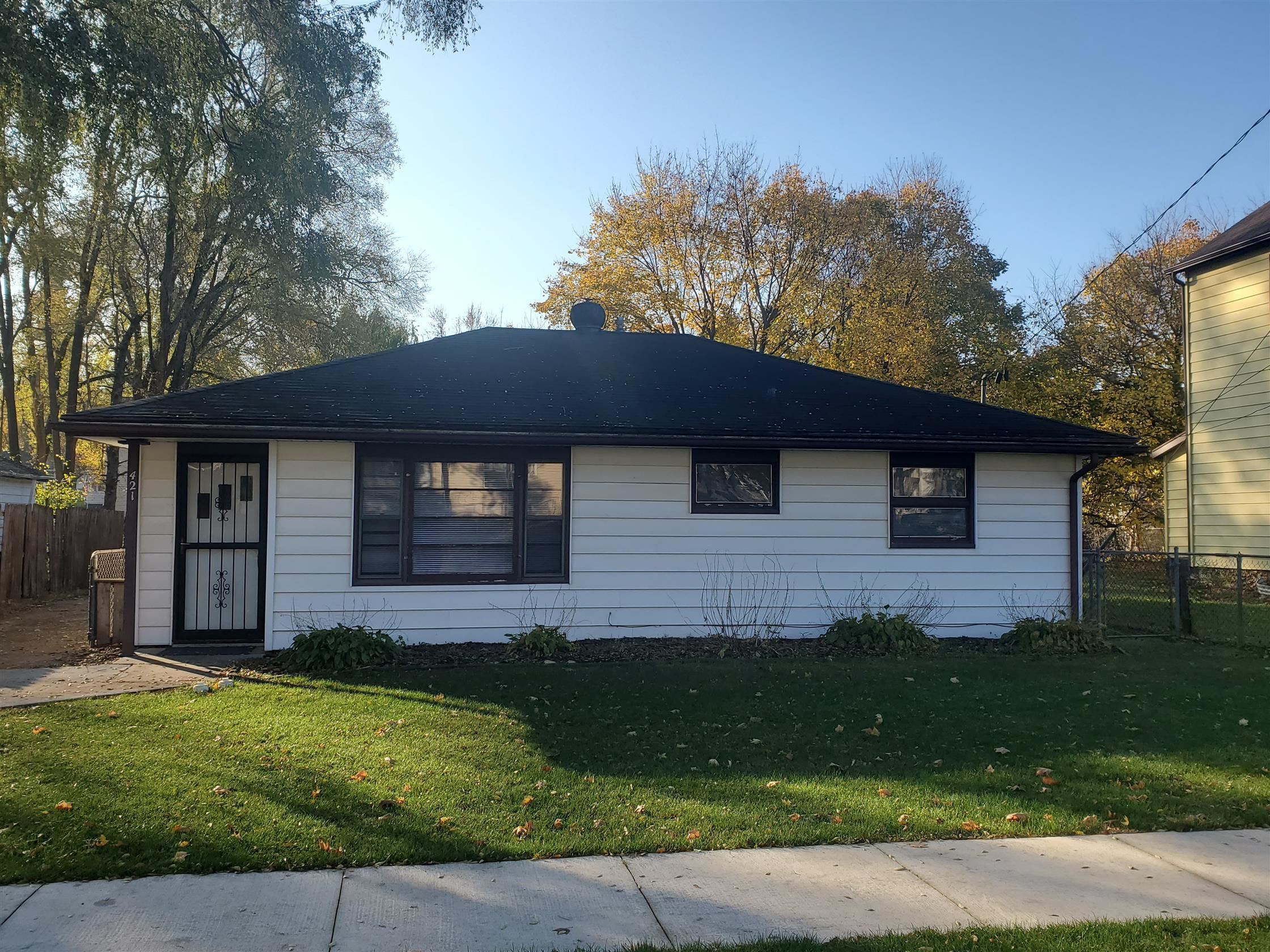 a brick house next to a yard with a large tree