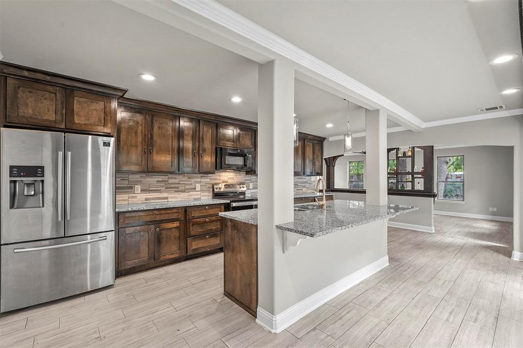 a kitchen with stainless steel appliances granite countertop a refrigerator a stove and a wooden floors