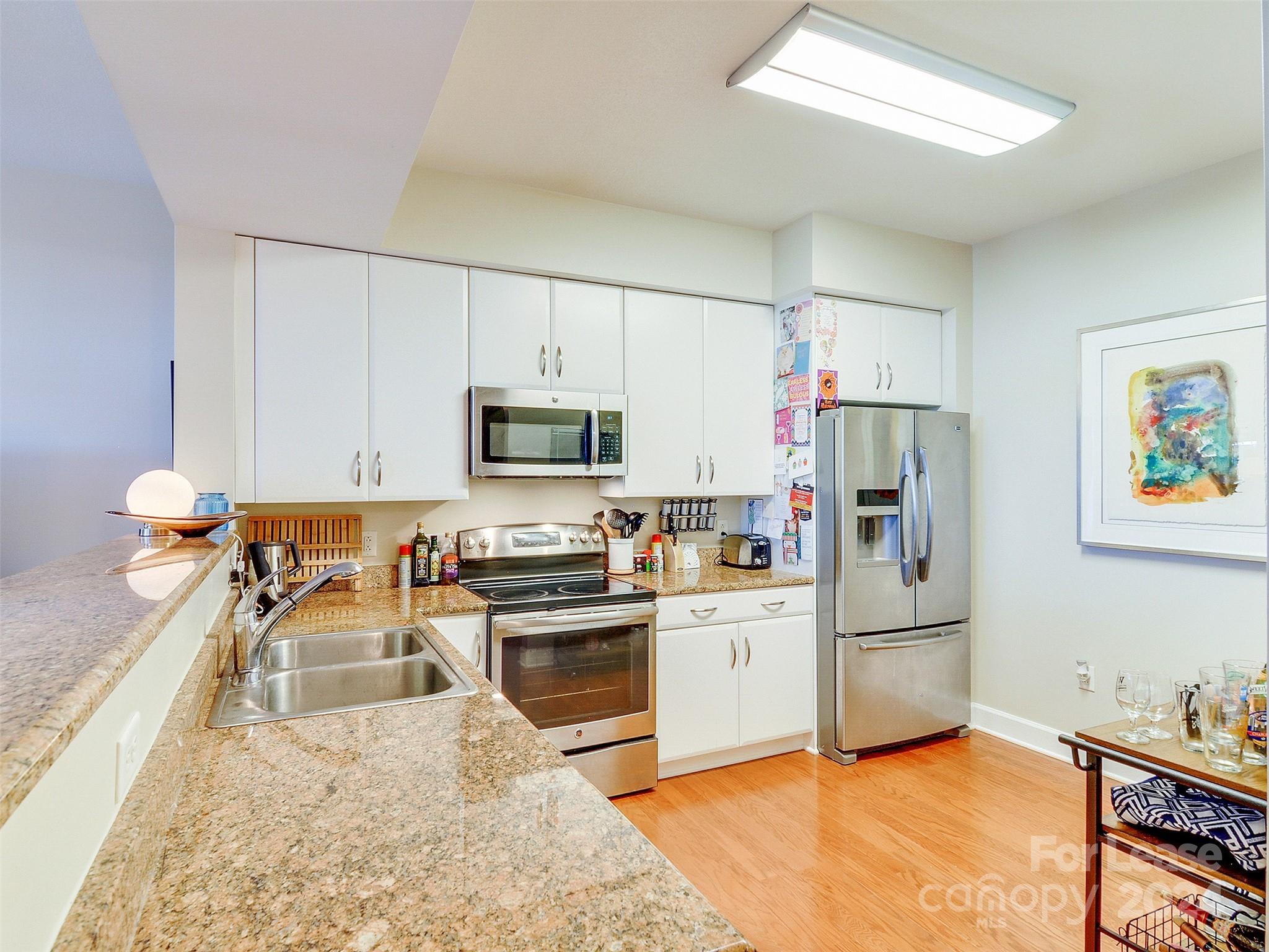 a kitchen with stainless steel appliances granite countertop a refrigerator stove microwave and sink