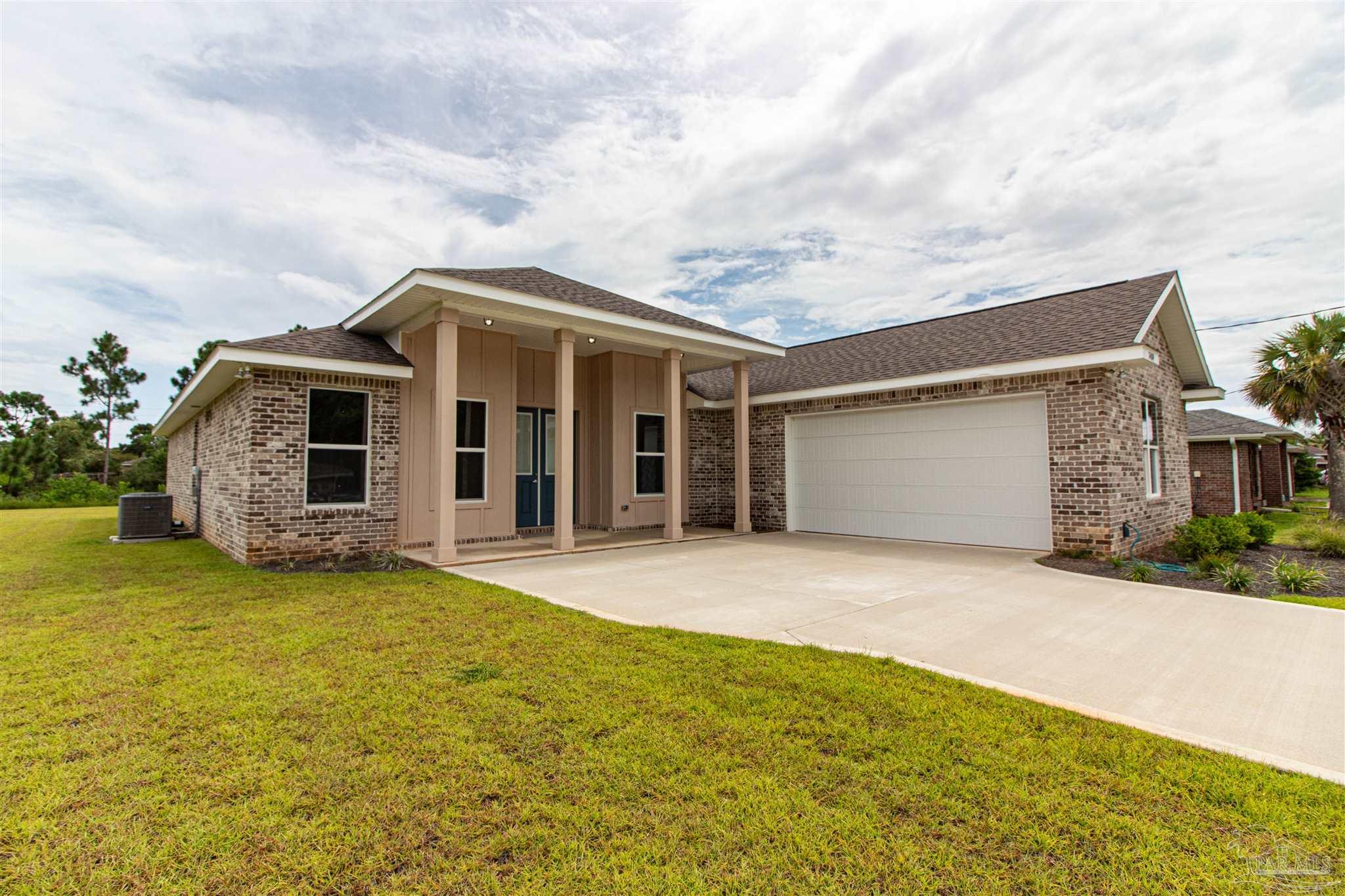 a front view of the house with yard and trees in the background