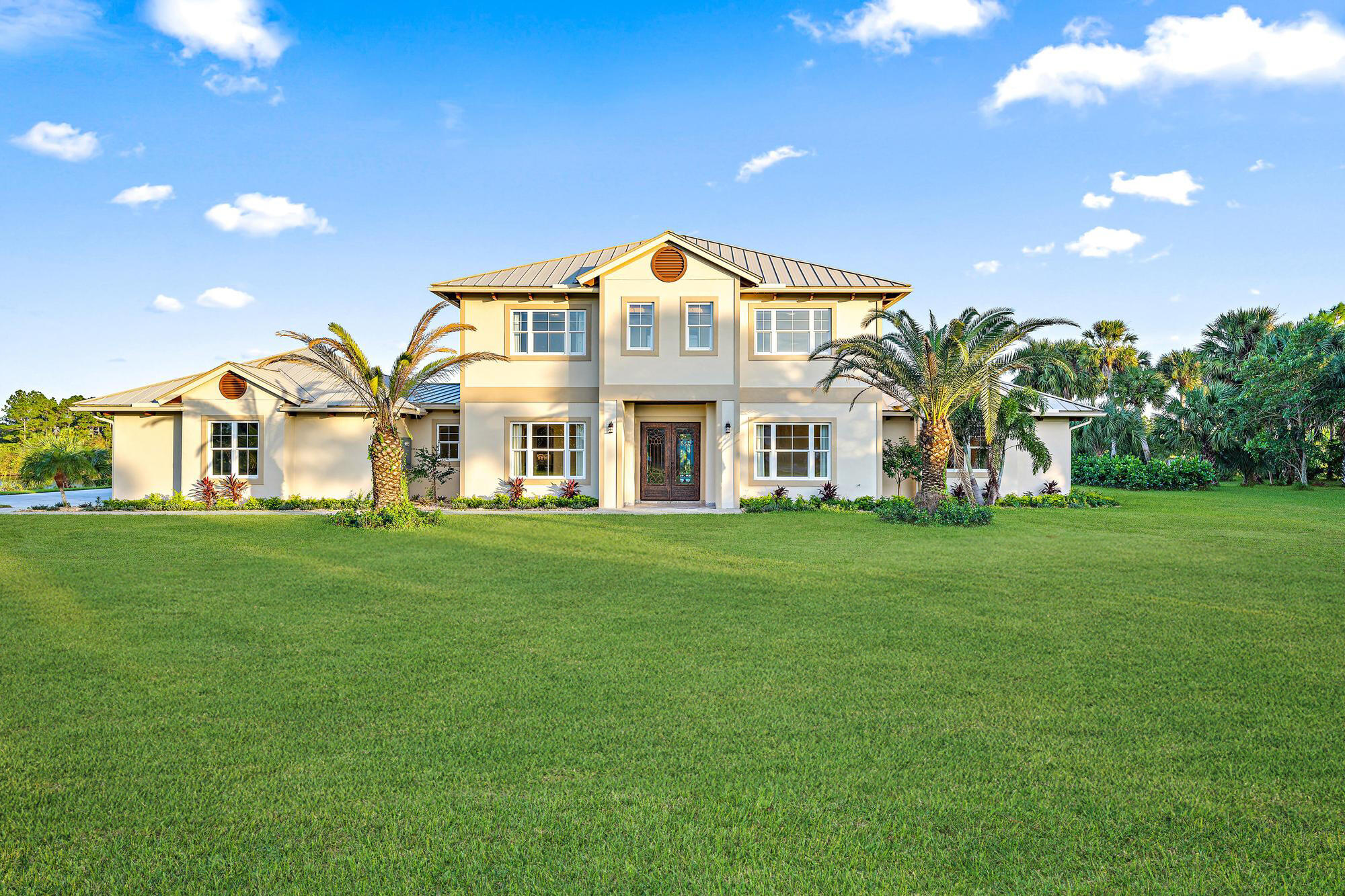 a view of a white house with a big yard and large trees