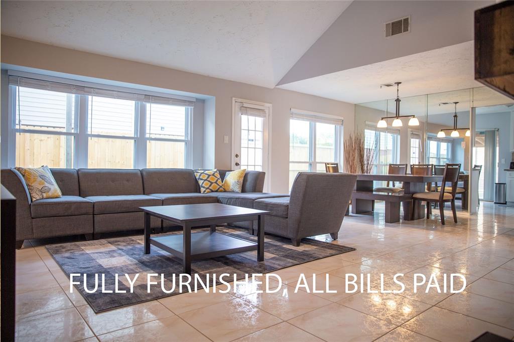 a living room with furniture a dining table and a large window