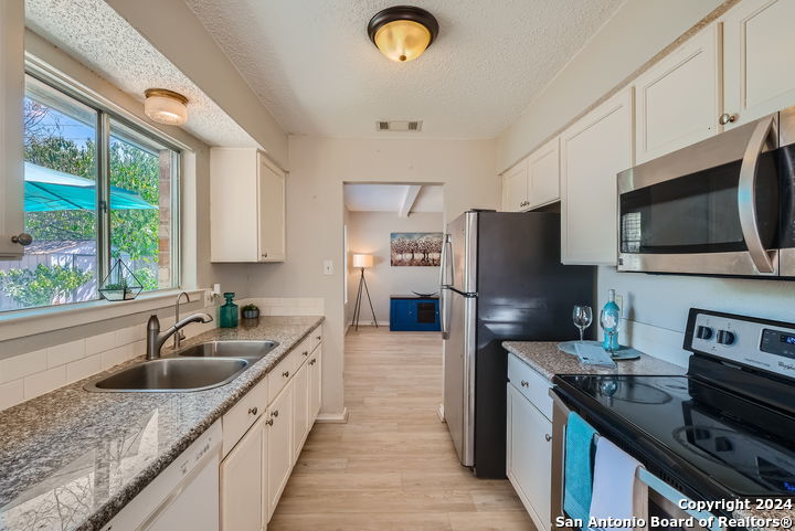 a kitchen with stainless steel appliances granite countertop a sink refrigerator stove microwave and cabinets