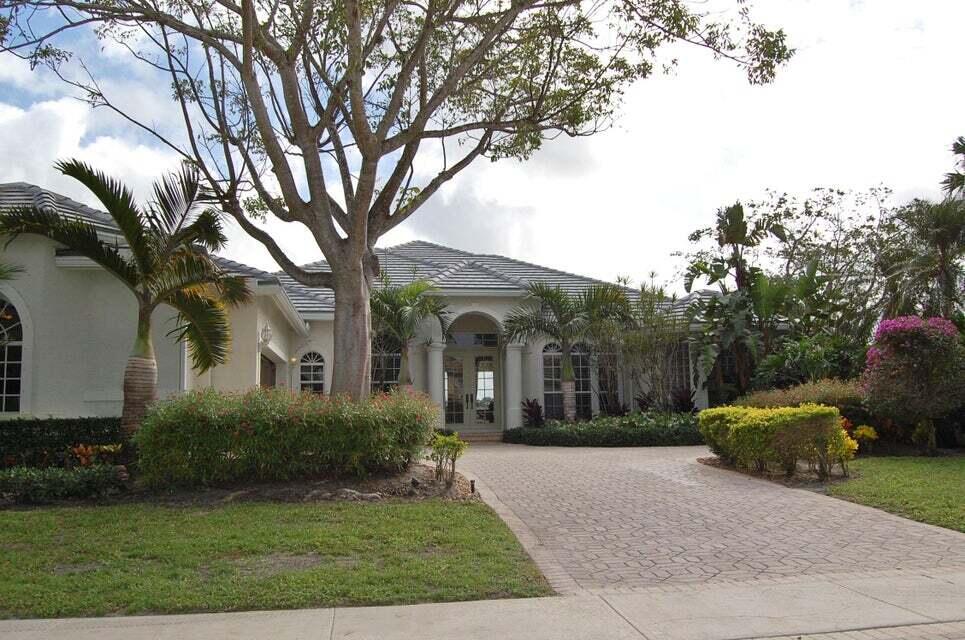 a front view of a house with garden and trees