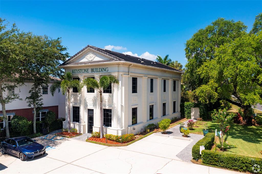 a view of a white house with a large windows and a small yard and large tree