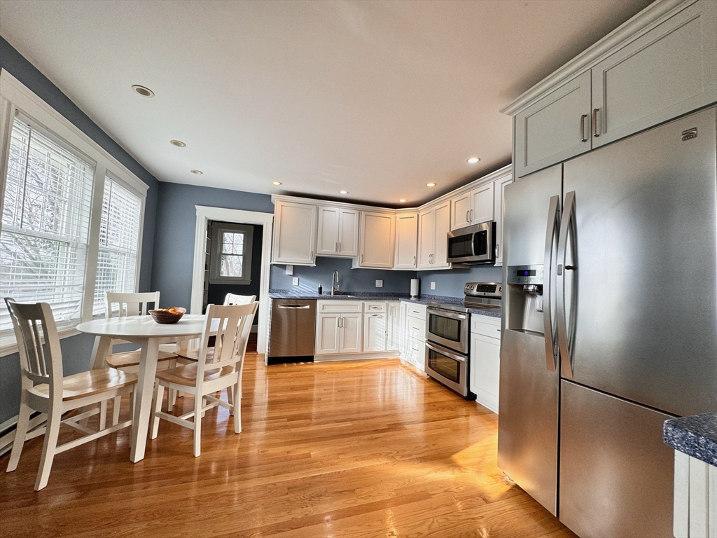 a kitchen with stainless steel appliances granite countertop a refrigerator a stove top oven a sink dishwasher and white cabinets with wooden floor