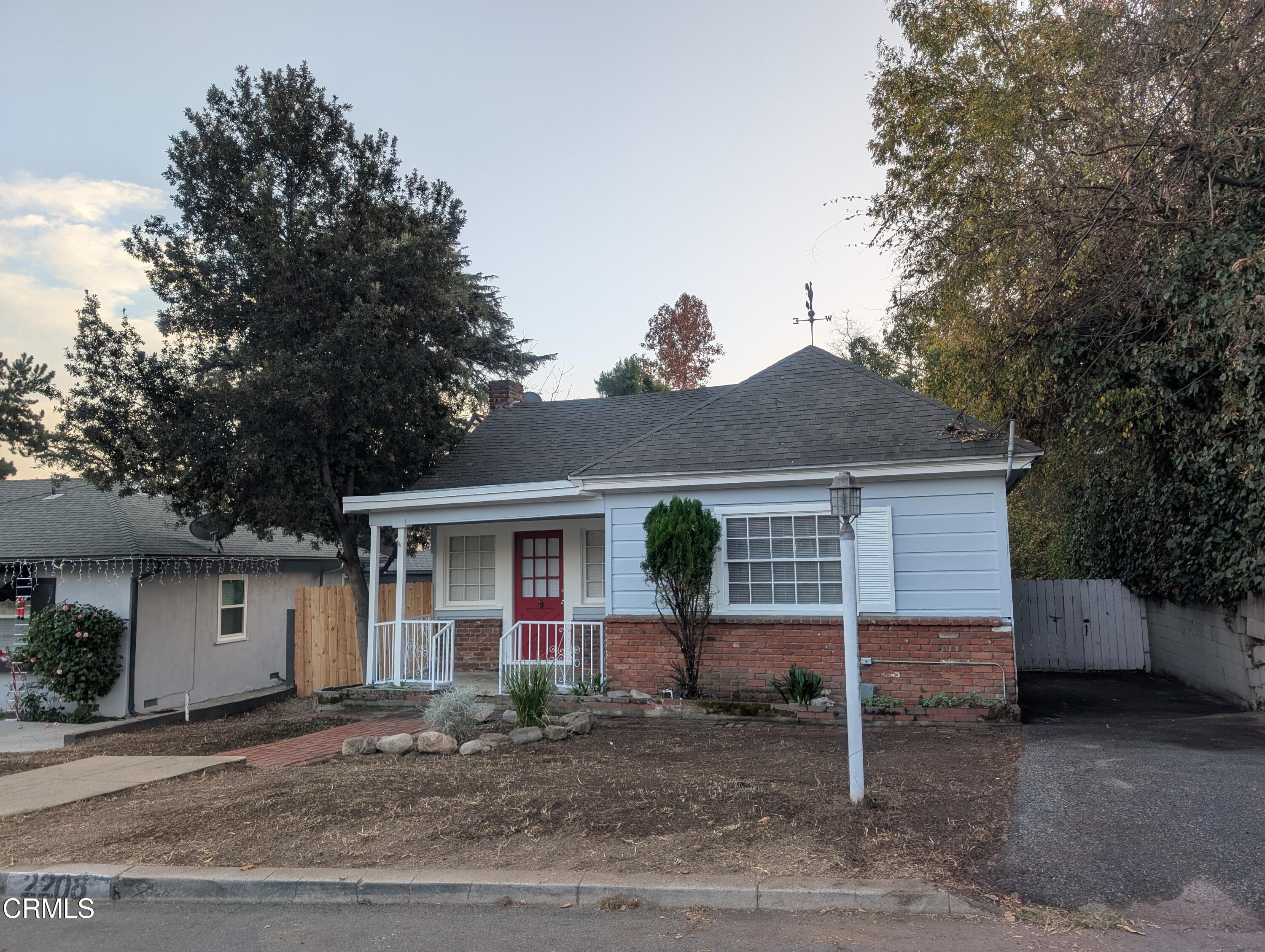 a view of a house with a yard and large tree