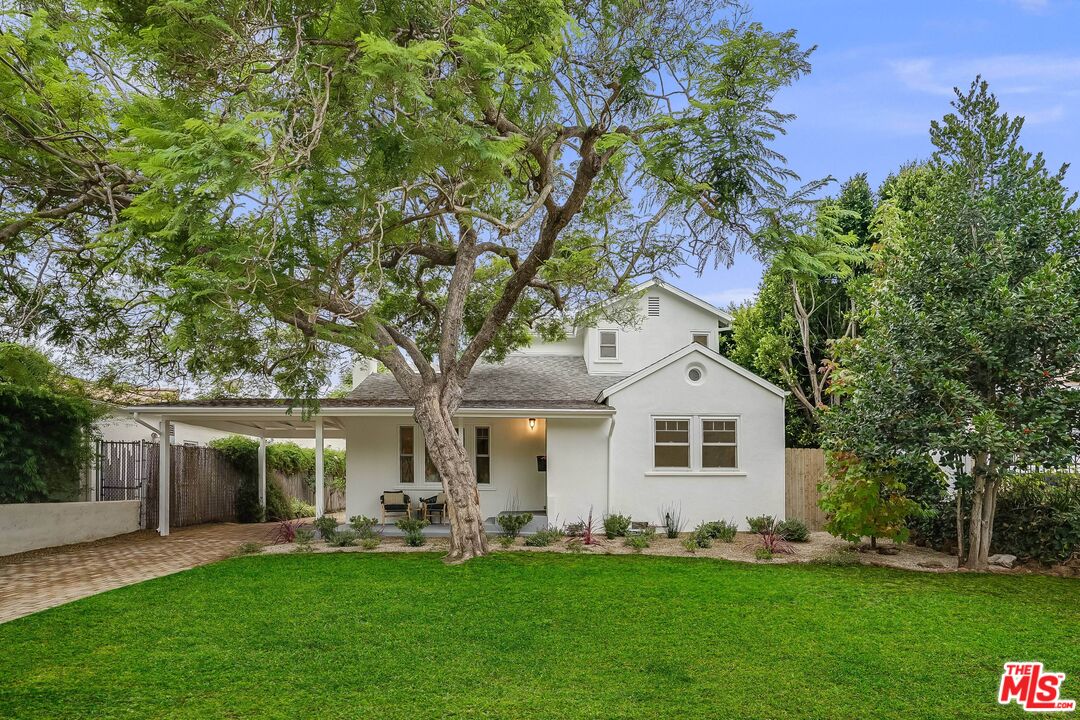 a front view of a house with a garden and trees