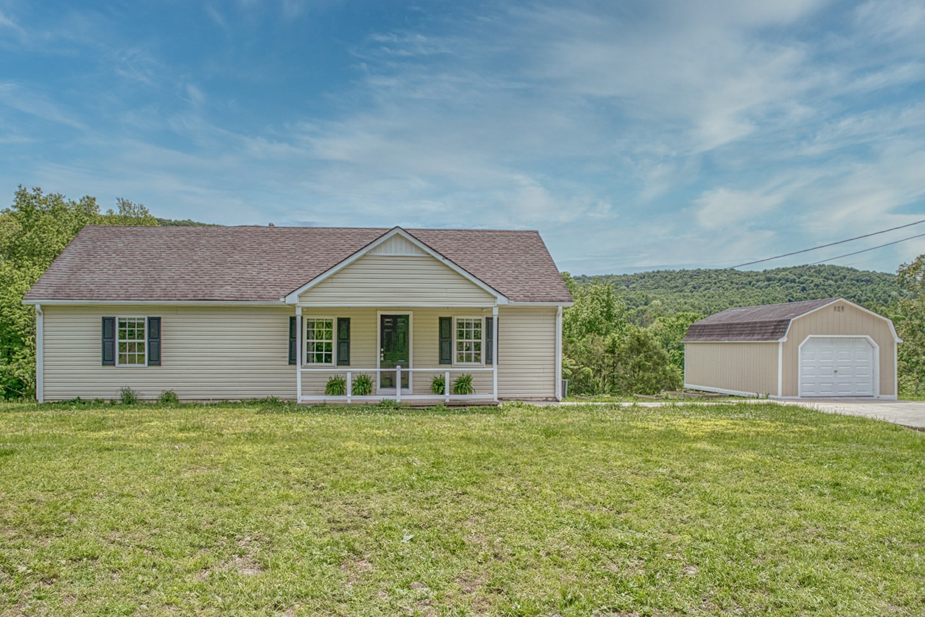 a front view of house with yard and trees in the background