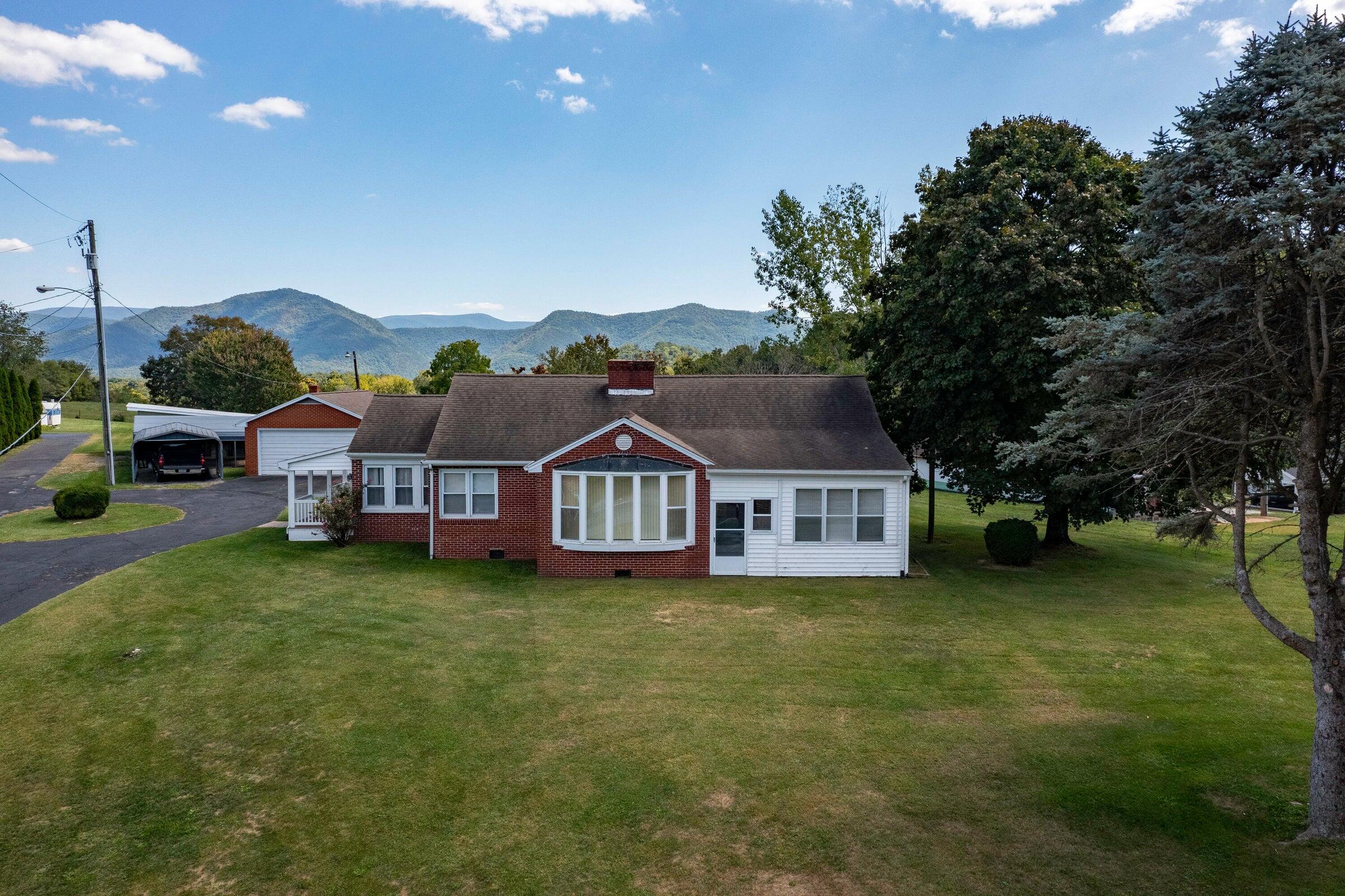 a view of a house with a big yard and large trees