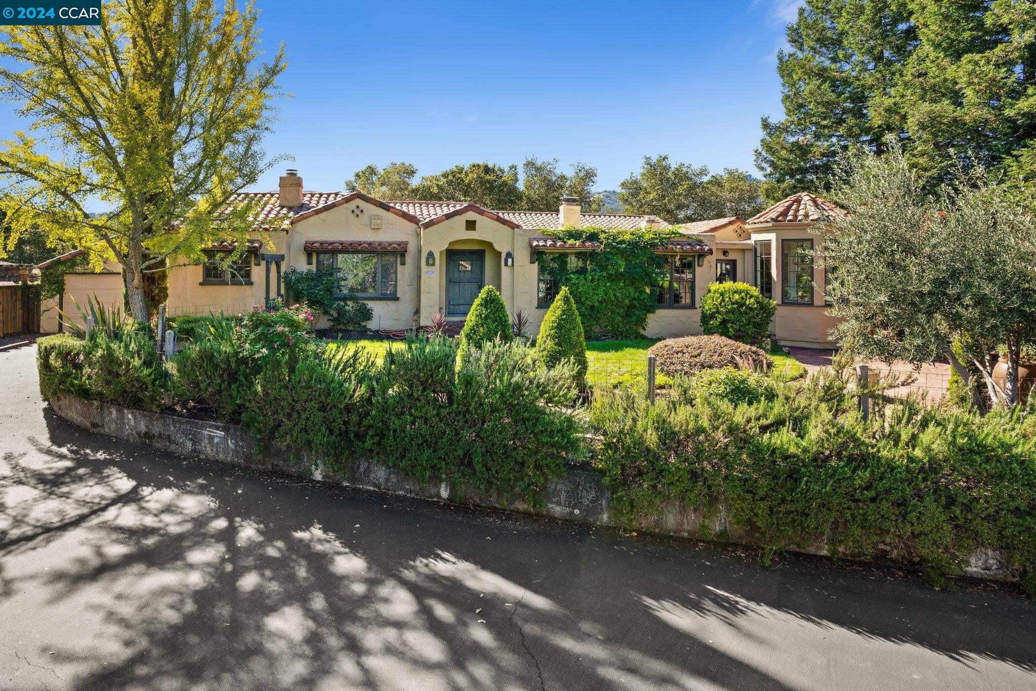 a view of a house with a small yard and large trees