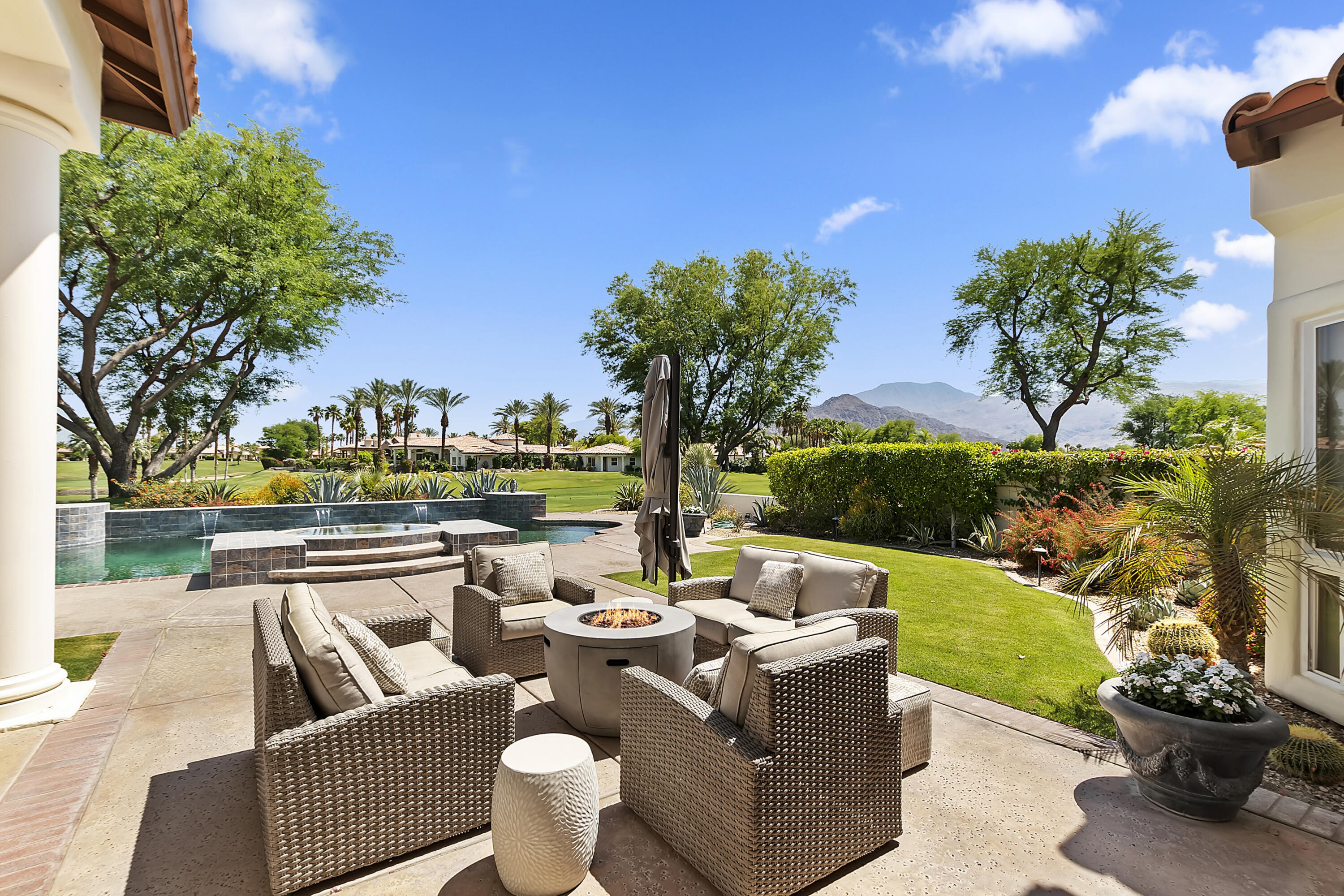 a view of a patio with couches chairs potted plants and a palm tree