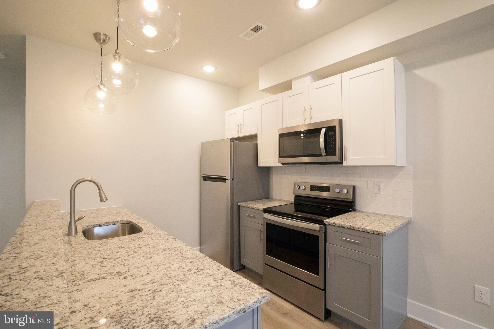 a kitchen with stainless steel appliances kitchen island a stove a sink and a microwave