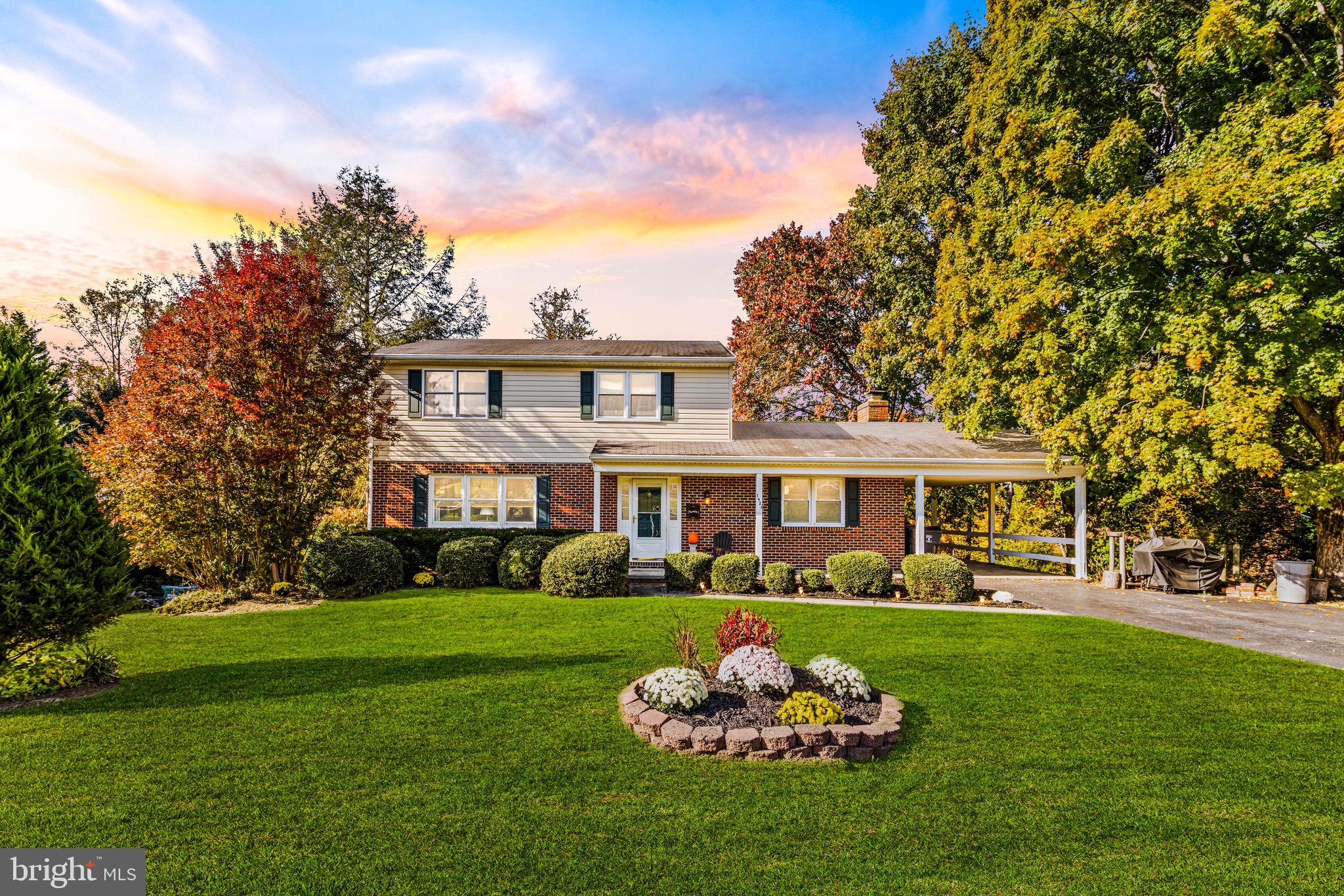 a front view of a house with a garden and trees