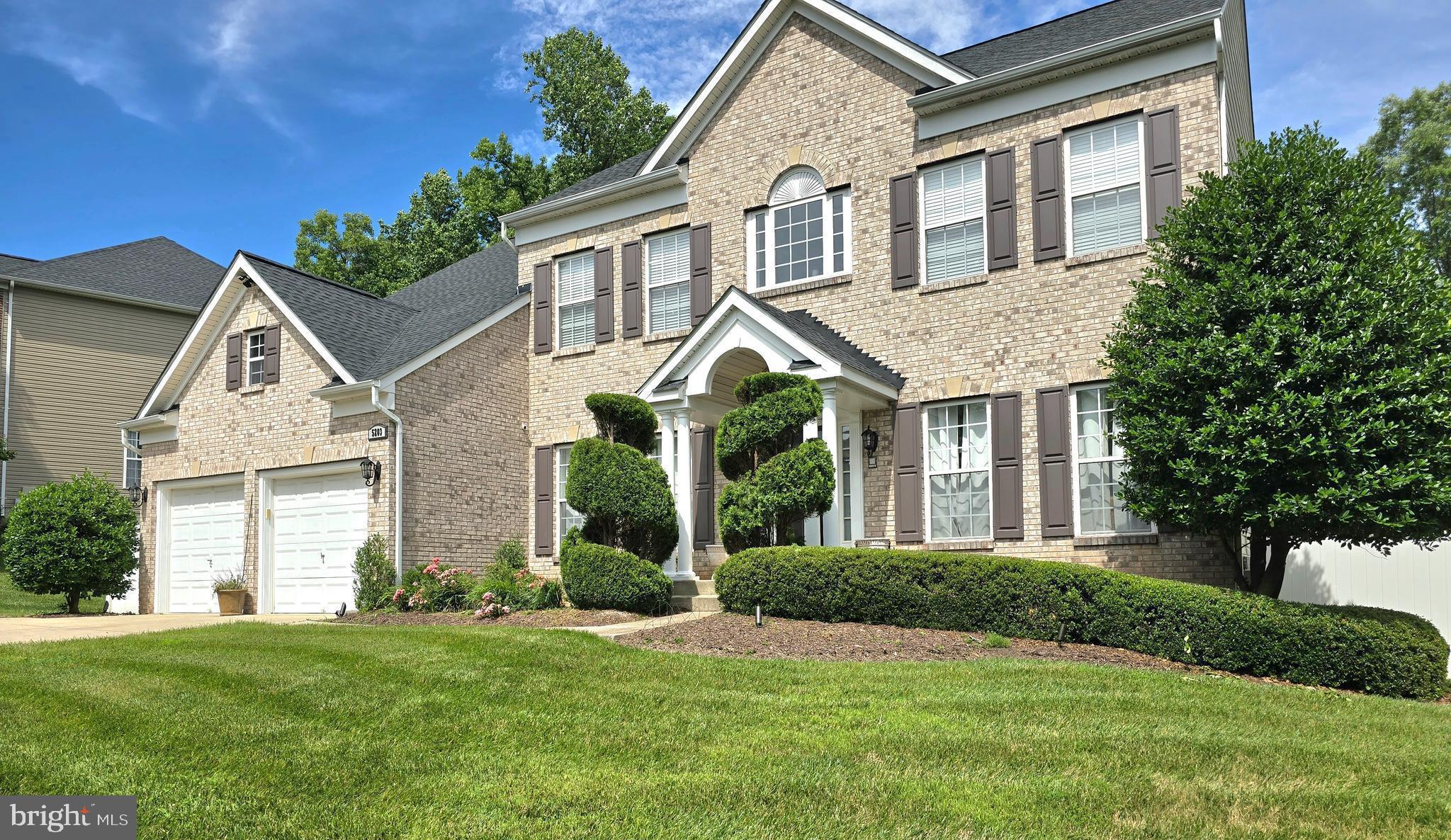 a view of a white house next to a yard with large trees