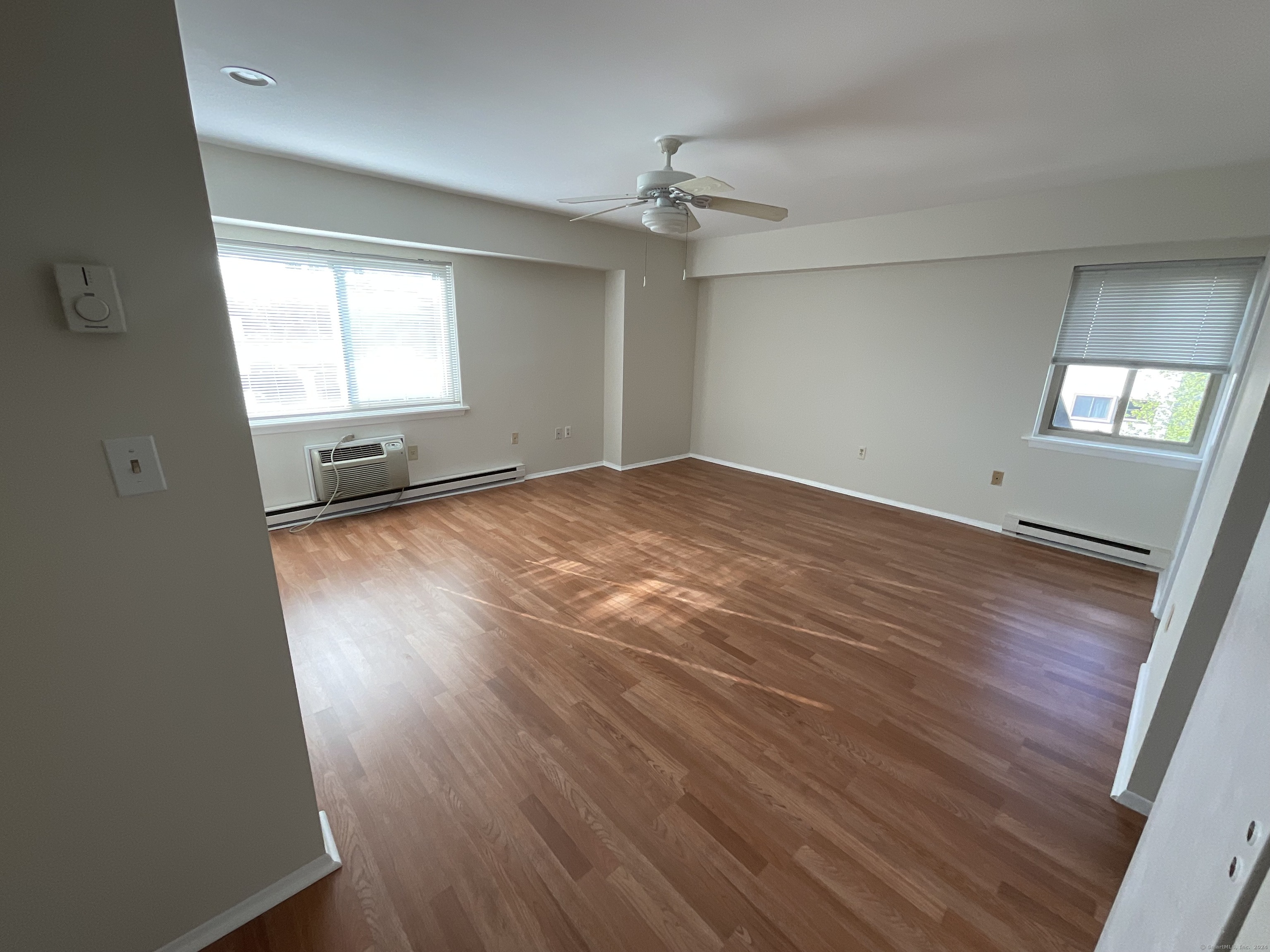 an empty room with wooden floor and windows