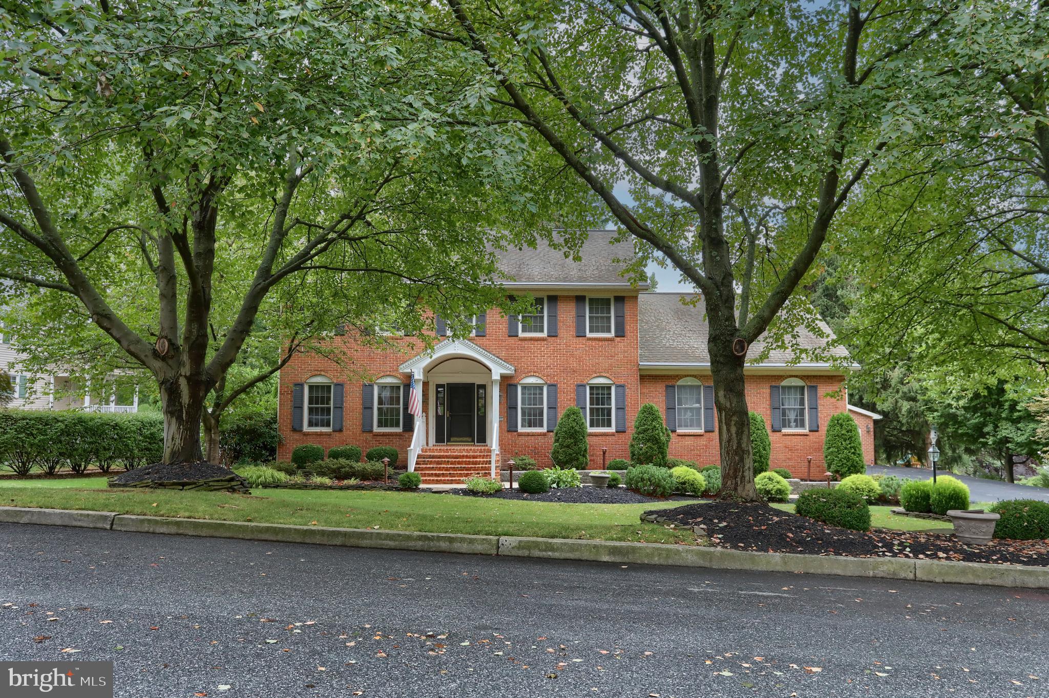 a front view of a house with a garden and trees