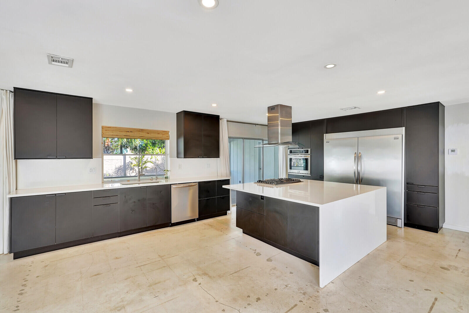 a large kitchen with stainless steel appliances a sink and a refrigerator