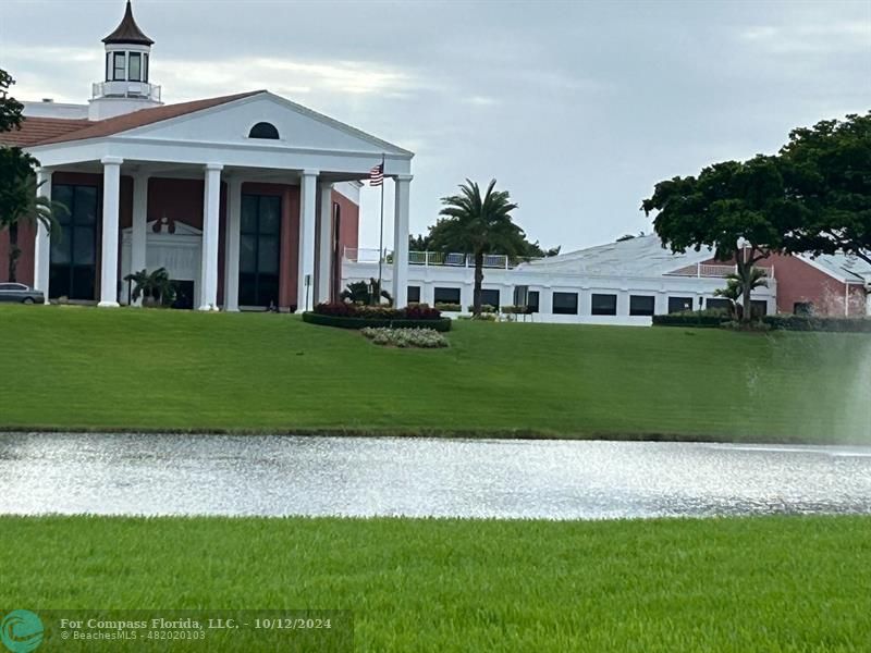 a view of a white house next to a yard with big trees