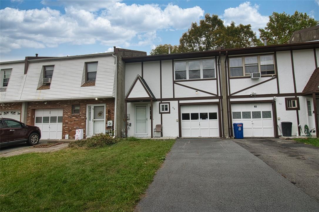 Multi unit property featuring a garage and a front lawn