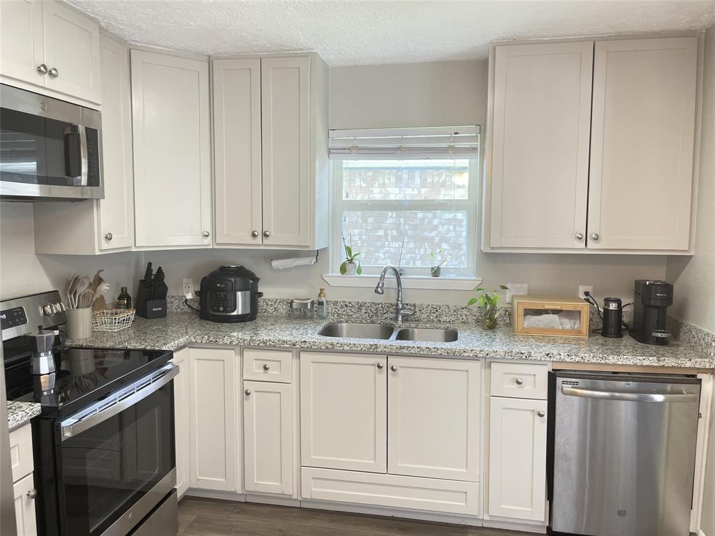 a kitchen with granite countertop white cabinets and white appliances