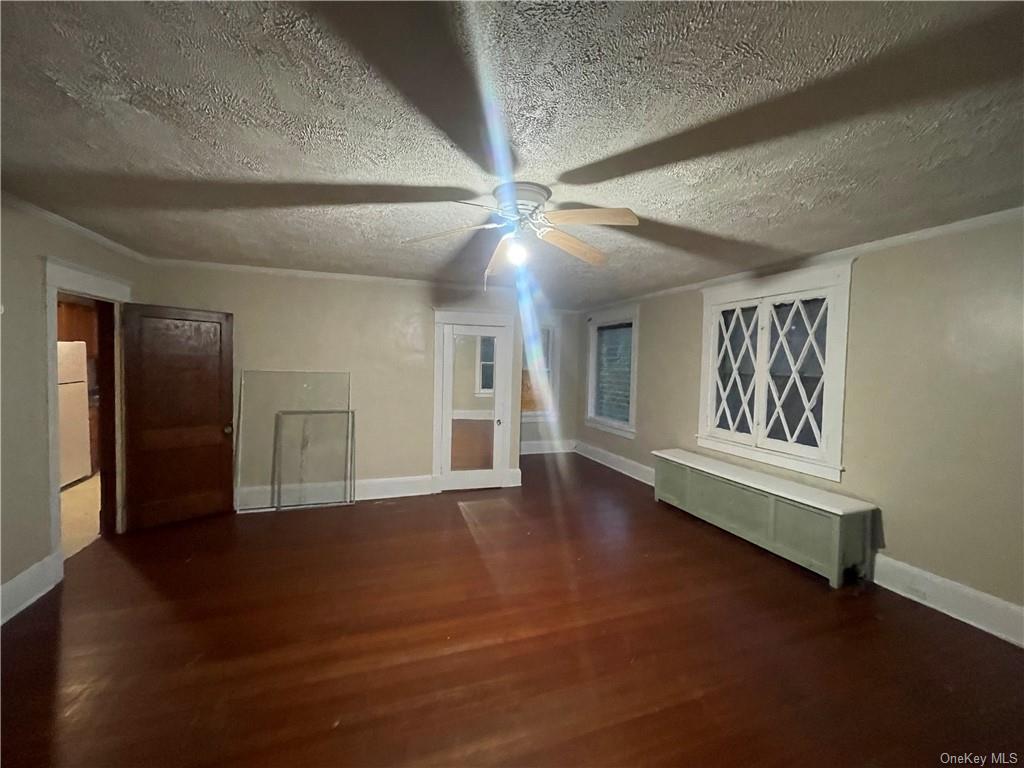 Bonus room with a textured ceiling, ceiling fan, and dark hardwood / wood-style flooring