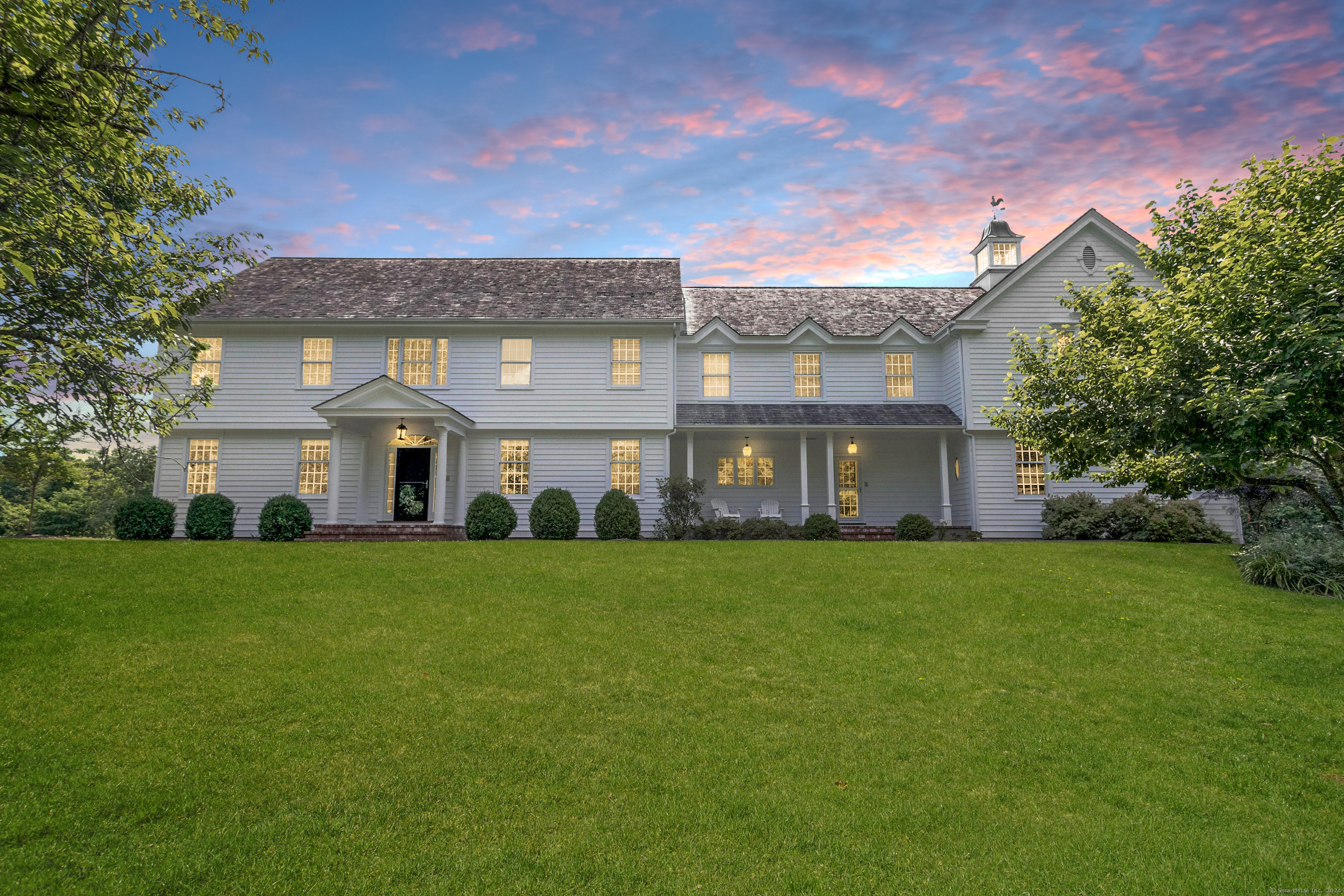 a view of a big house with a big yard and large trees