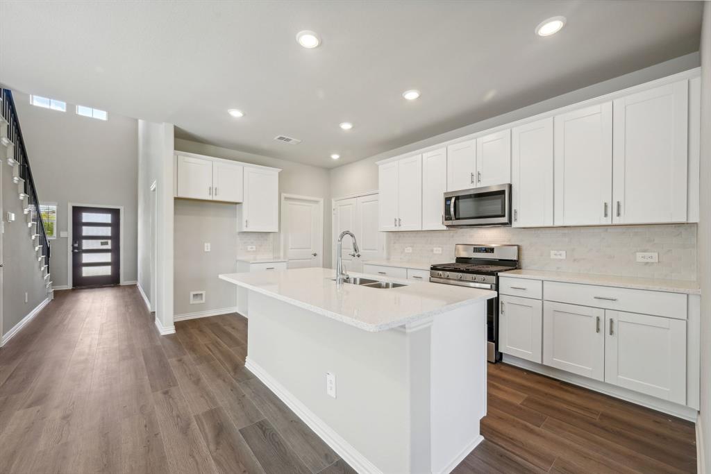 a kitchen with stainless steel appliances white cabinets a sink a stove a refrigerator and white cabinets